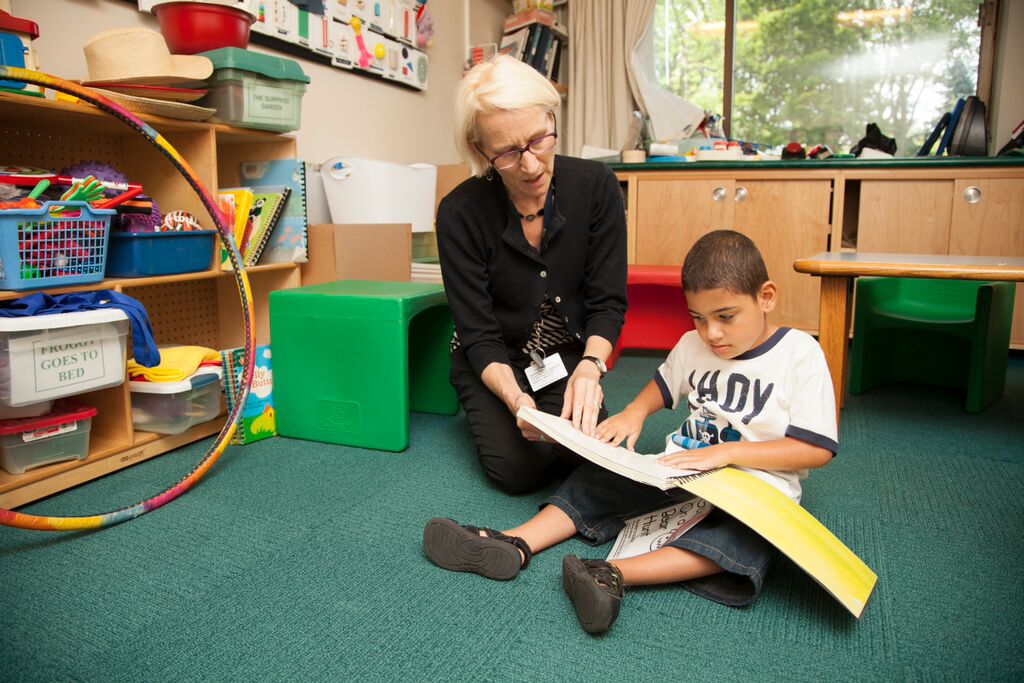 Teacher with a young boy looking at a braille book