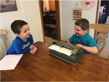 Brothers using brailler at table
