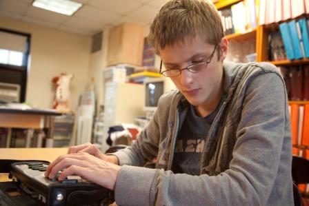 A teenage boy uses a braille notetaker