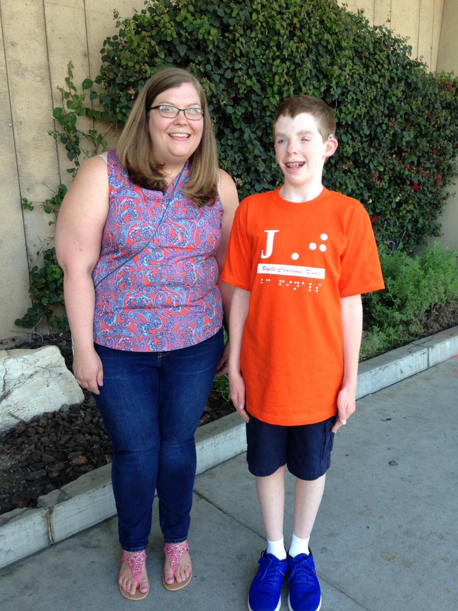 a visually impaired boy standing with his teacher