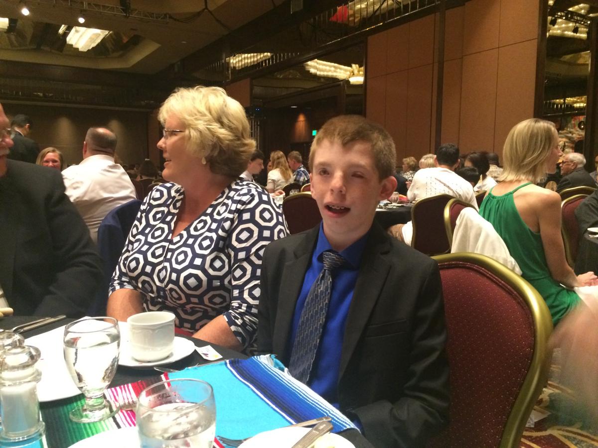 a boy with an adult sitting at the table at the gala