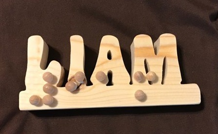 Liam written in wood lettering with wood dots for braille