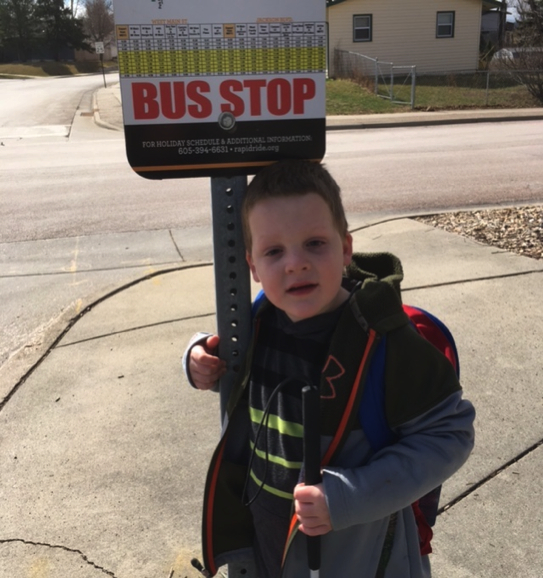 A boy stands at the bus stop