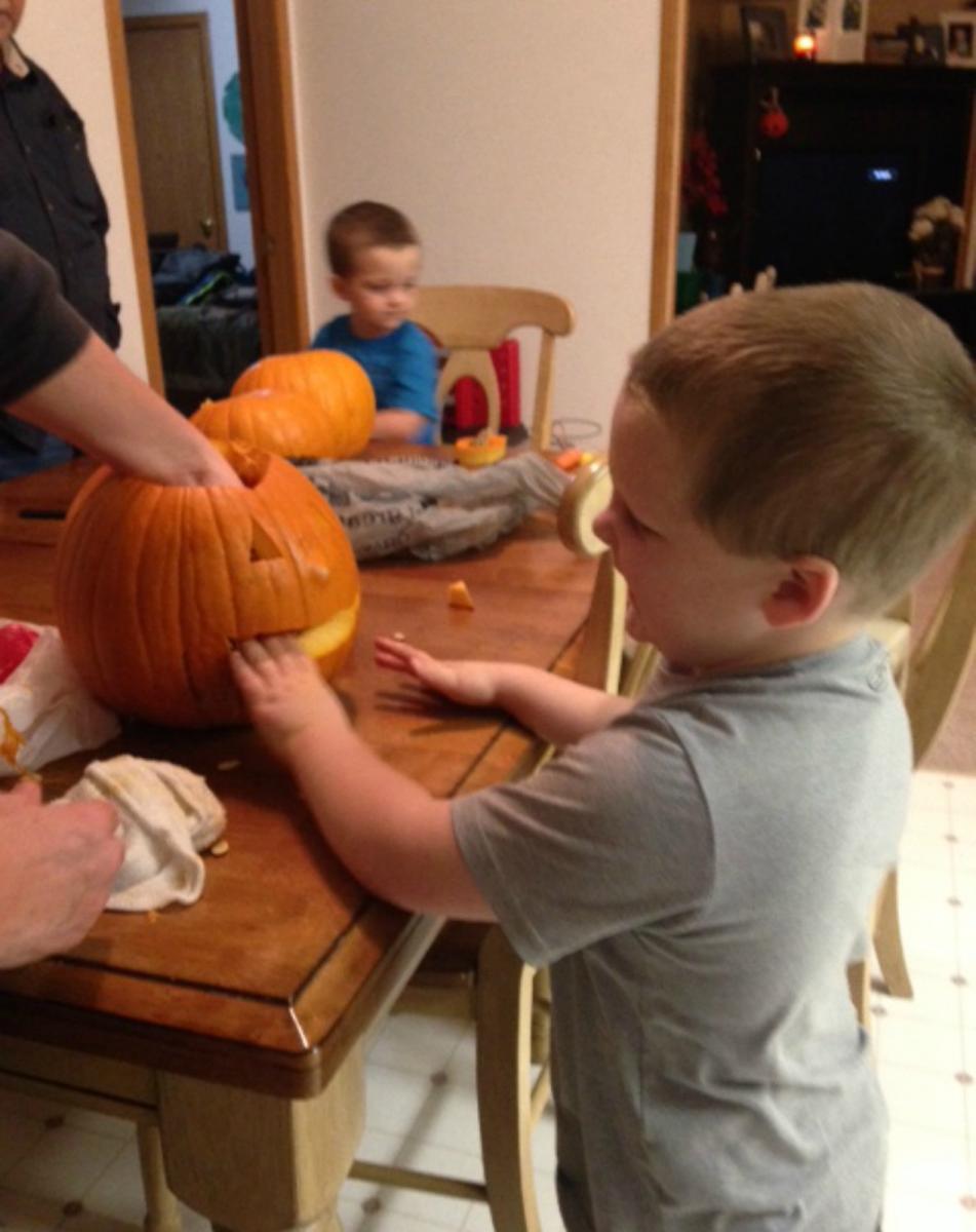 boy feeling carved pumpkin