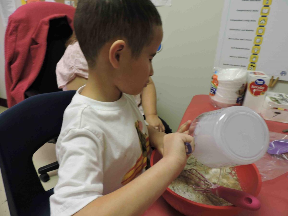 Pouring water in mix Setting up cooking activity in classroom