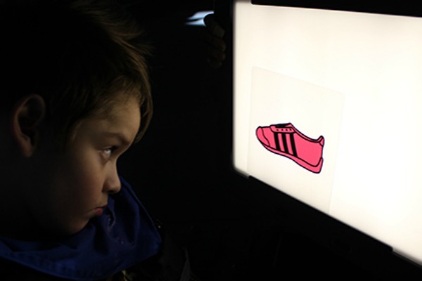 Child looking at red shoe on lightbox