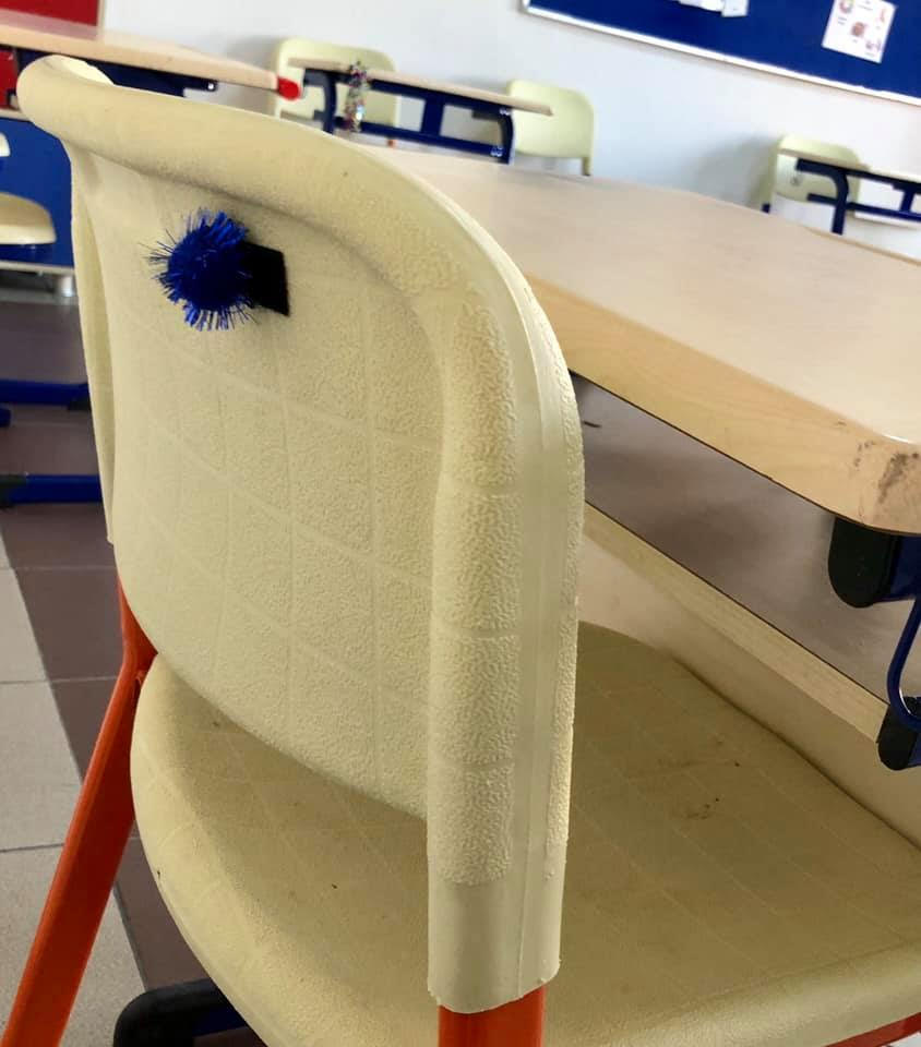 A blue koosh ball on the back of the chair is the symbol for a particular student.