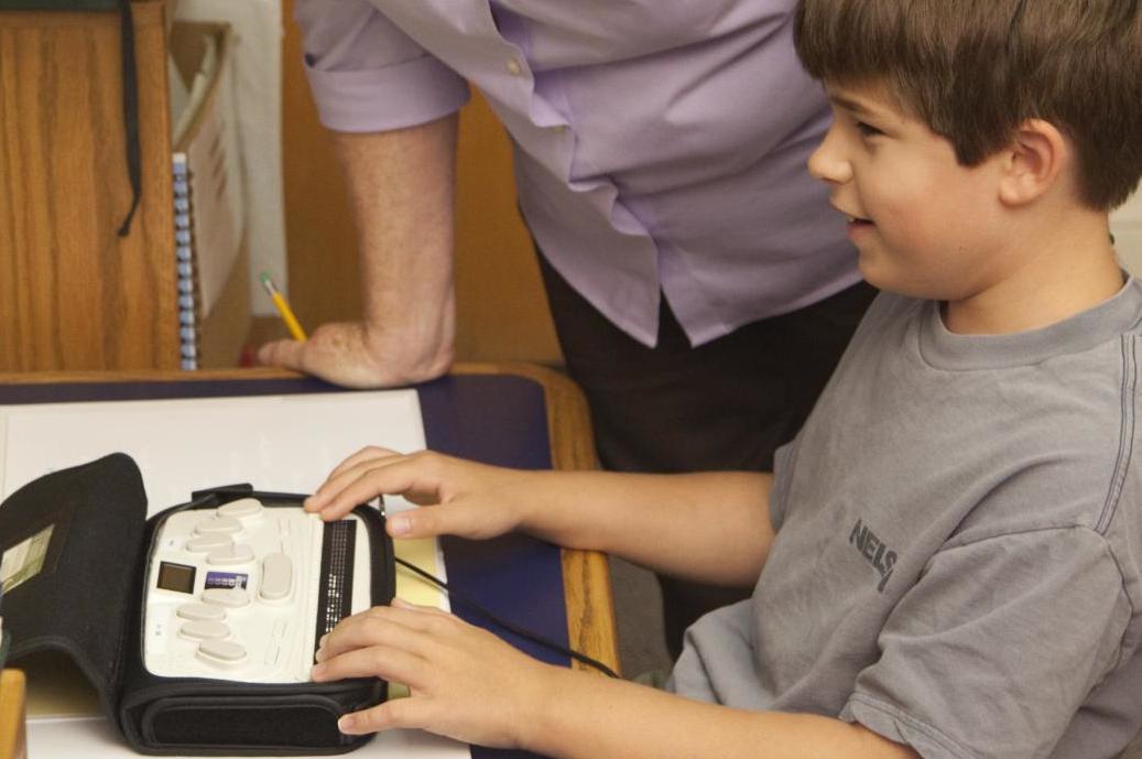 boy in gray shirt using braillewriter