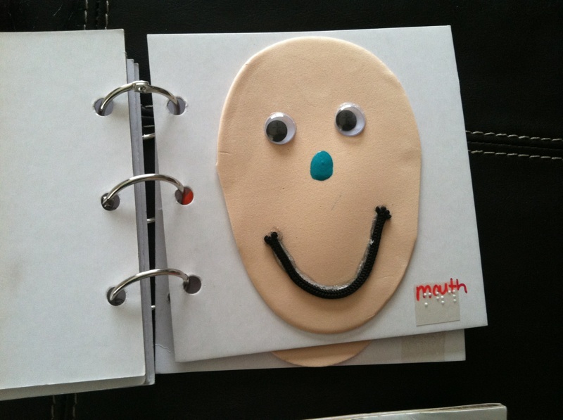 Tactile book of a face with braille label "mouth"