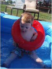 A young boy uses a floaty in a wading pool.
