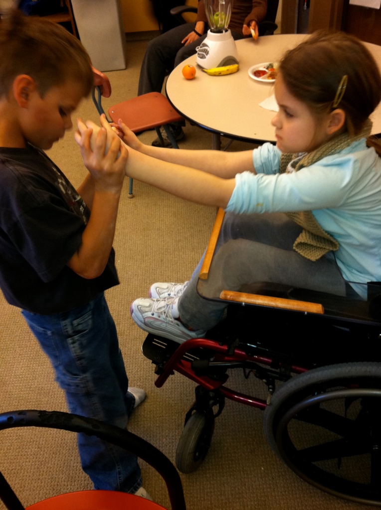 A boy feels the outstretched hands of a girl in a wheelchair