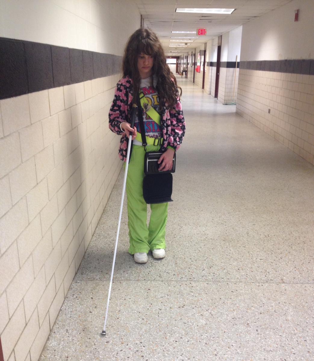 Girl using cane while traveling in hallway