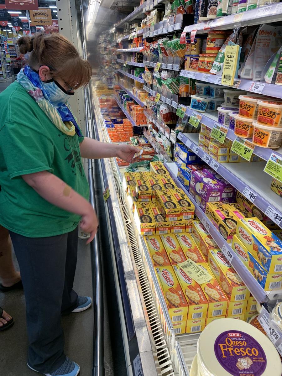 A student matches the picture card to the grocery item in the store.