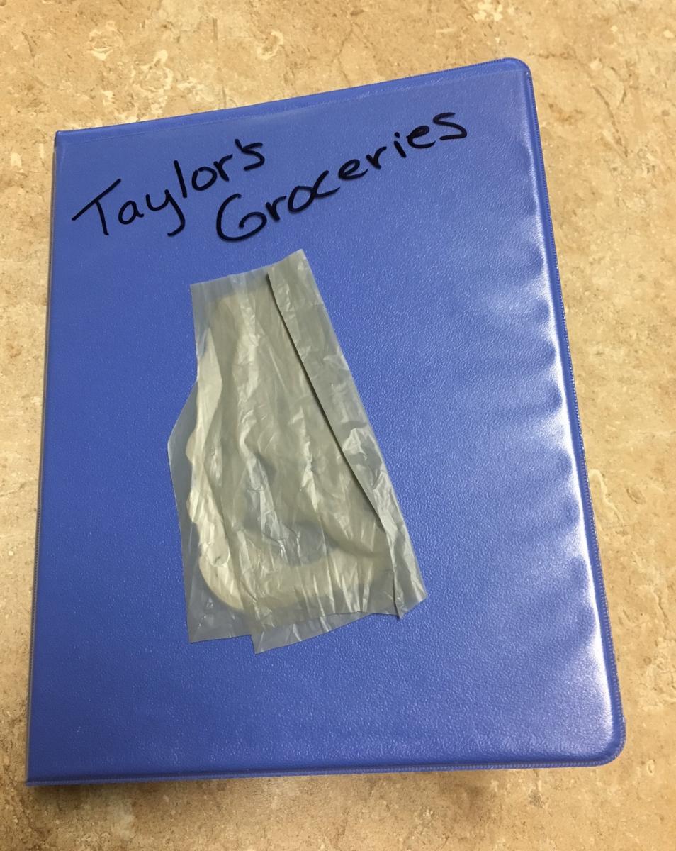 The cover of the mini binder has a piece of a shopping bag on it. a small binder labeled