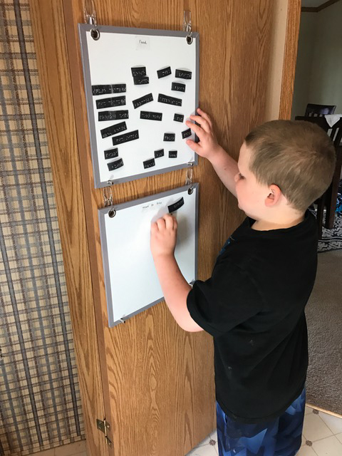 Liam putting grocery items on a magnetic board