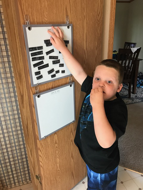Liam reading and signing items on Liam moving grocery items on the magnetic board