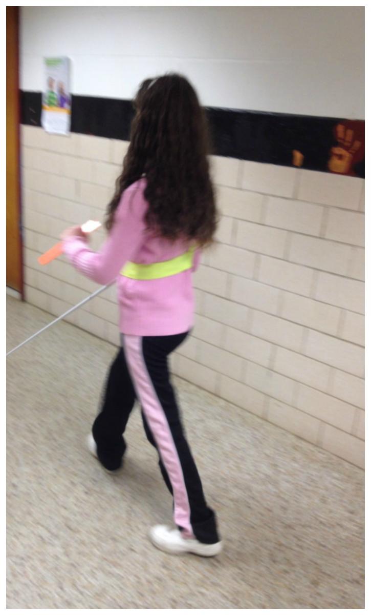 student walks using cane in hallway