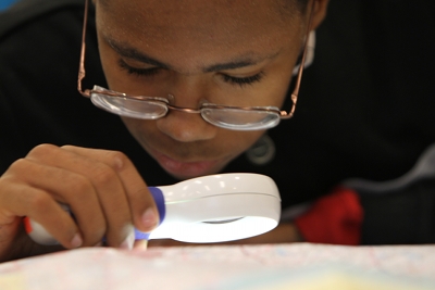 A boy uses a handheld magnifier