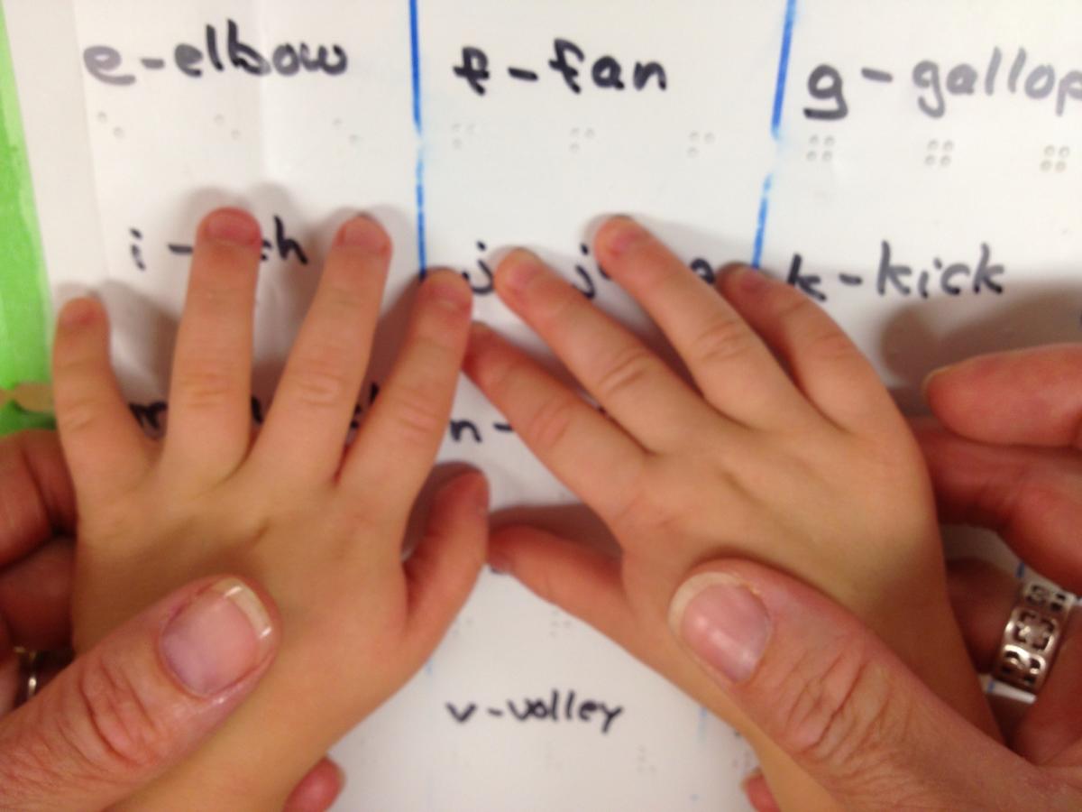 Small child's hands touch braille with an adult's hands