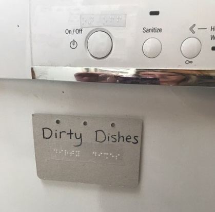 a magnet on a dishwasher that says dirty dishes in print and braille