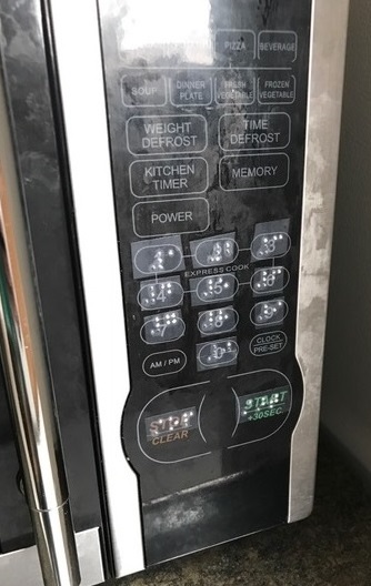 a microwave panel with braille labels over the buttons