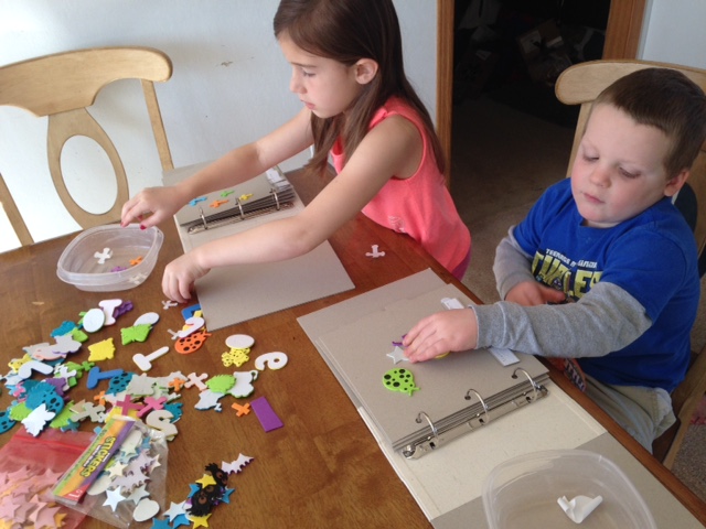 Two children illustrate pages with tactile stickers