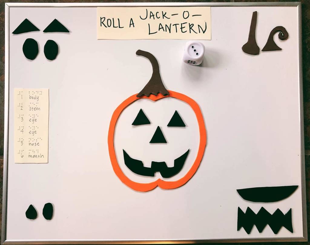 A white board with black foam pieces needed to create a jack o latern