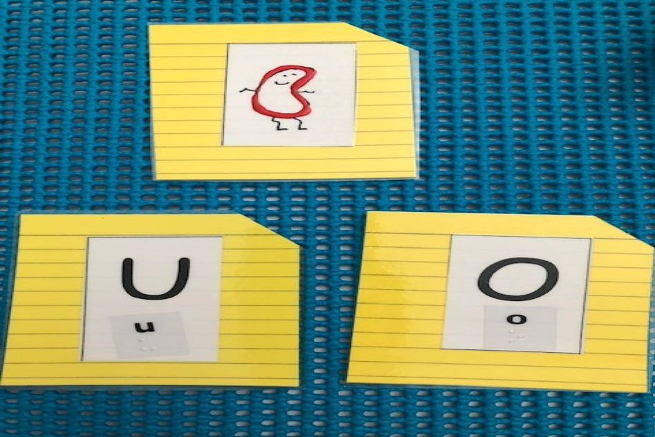Three cards: Jumping bean card, and print & braille cards for the letters u and o