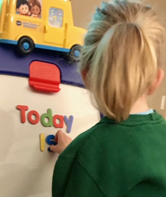 A girl with a pony tail manipulates letters spelling out 