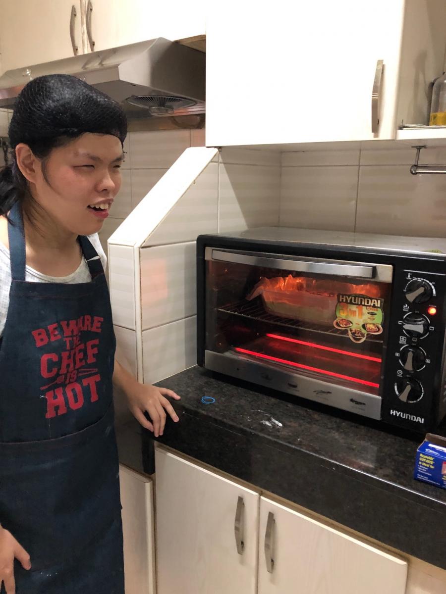 Kara stands by the oven while her goods cook.