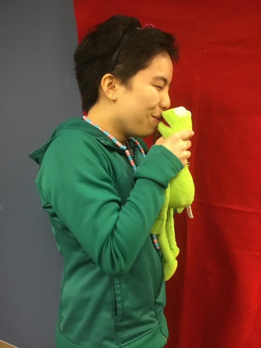 Teenage girl holding Kermit the frog close to her mouth