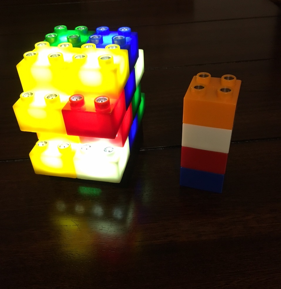 legos with lights inside of them build into a tower next to a legos that are not lit up