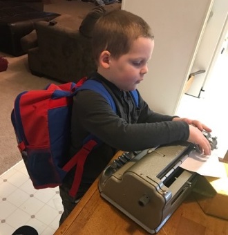 Liam using his brailler to label the envelope. 