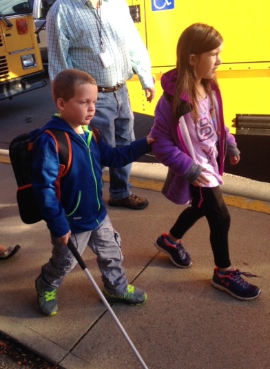 liam walking with cane next to girl