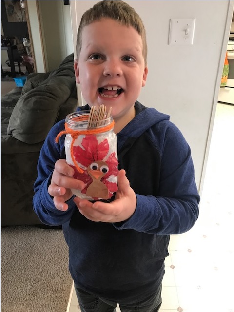 Liam holding his finished Liam standing and showing off his final turkey jar