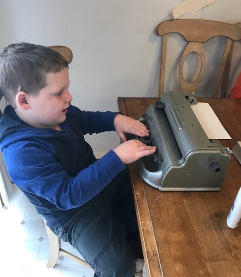 Liam uses his brailler to make a list of what he is thankful for. Liam writing with his brailler