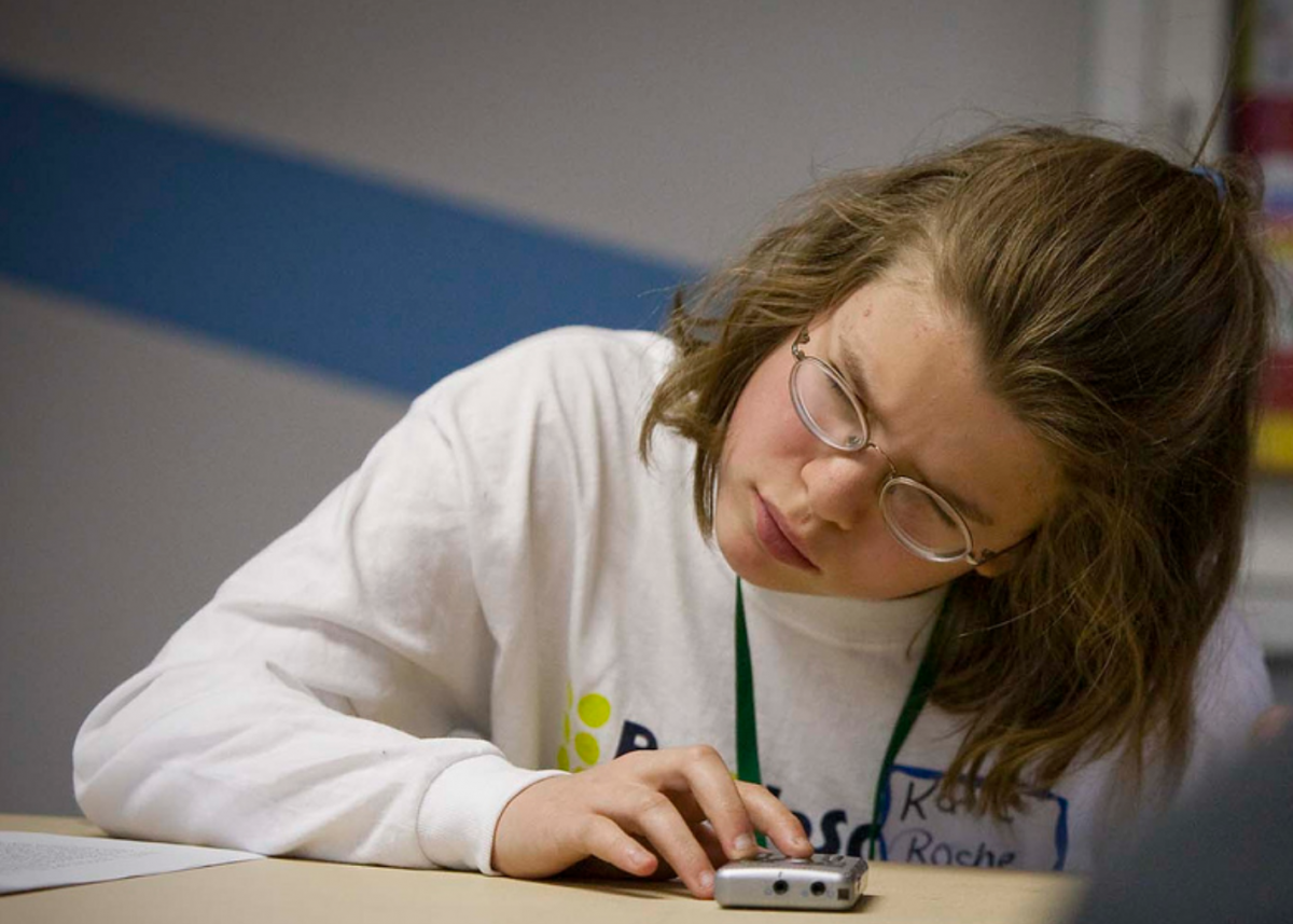 A girl with glasses uses an audio device.