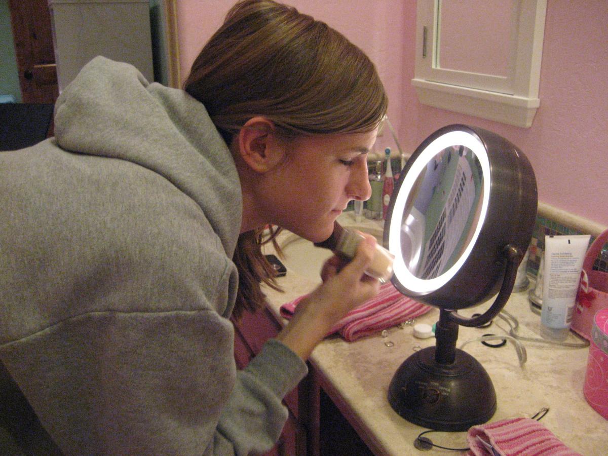A teenaged girl puts on her make up