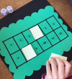 Taking a sticky note the math game board with two spaces covered