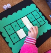 Placing sticky note over number she rolled game board with student placing a piece over one of the squares