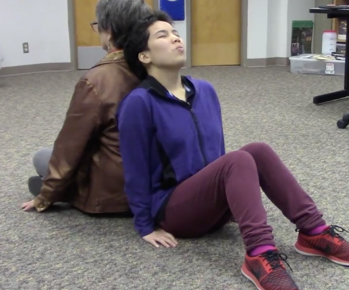 Two people sitting on the floor leaning back-to-back
