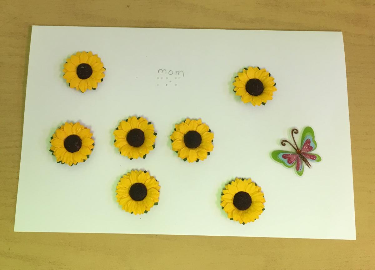 a card for mother's day with sunflower stickers, a butterfly sticker, and Mom in braille