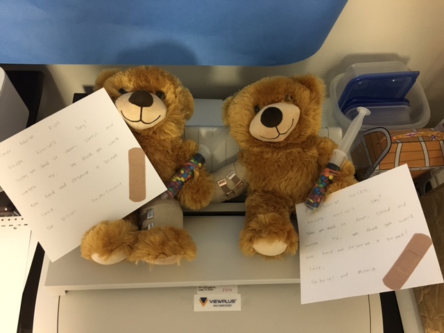two teddy bears with ace bandages, candy filled syringes, and brailled notes