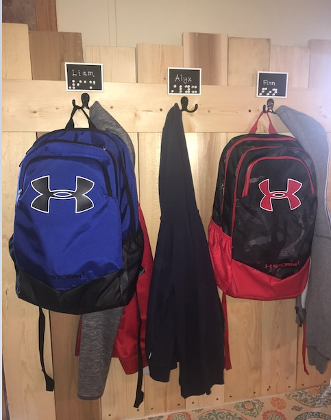 backpacks hanging on the hooks above the organization bench