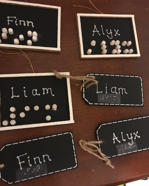 name tags written in print and braille with wooden pegs