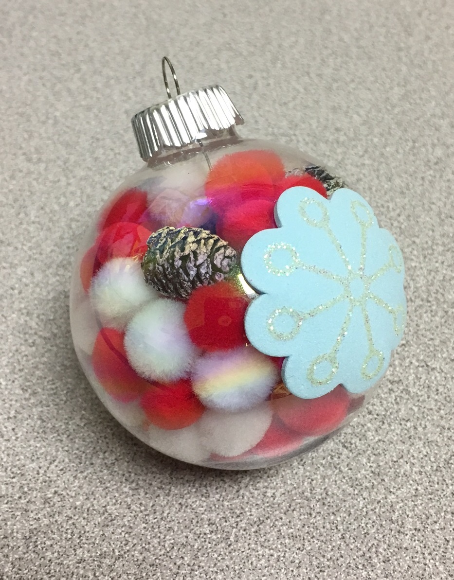 a glass ornament filled with red and white pom poms