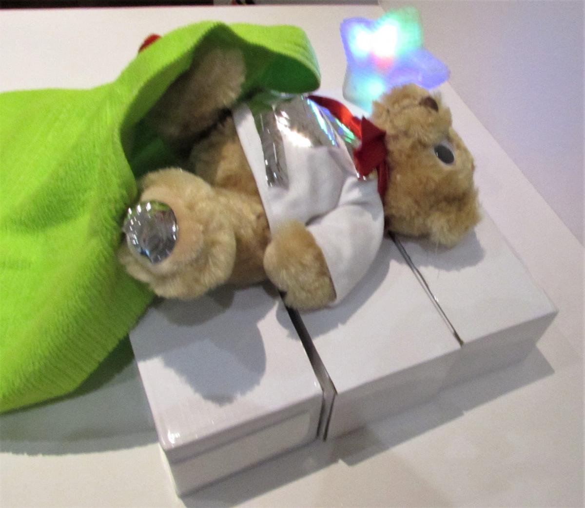 a stuffed toy bear on a bed made of cardboard boxes and a green blanket
