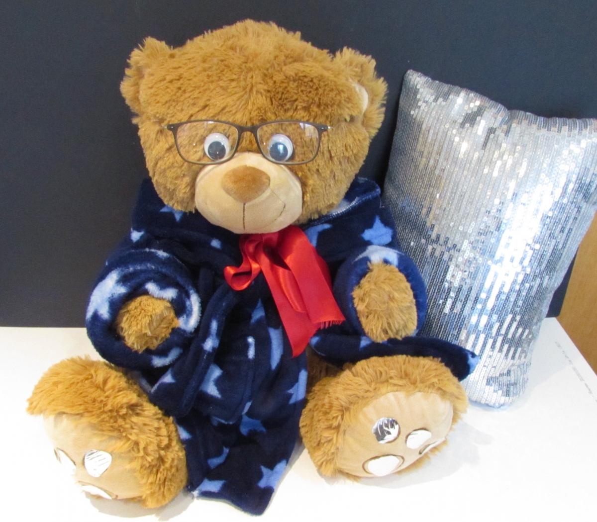 Mr. Bear wearing glasses and a shiny throw pillow