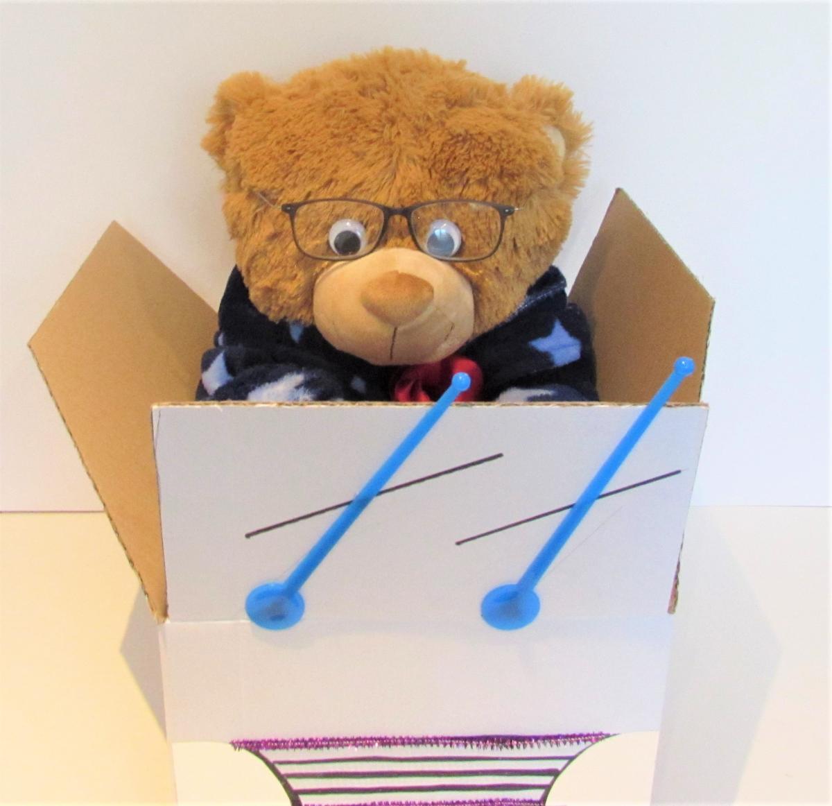 a teddy bear with glasses in a car made out of a cardboard box with windshield wipers