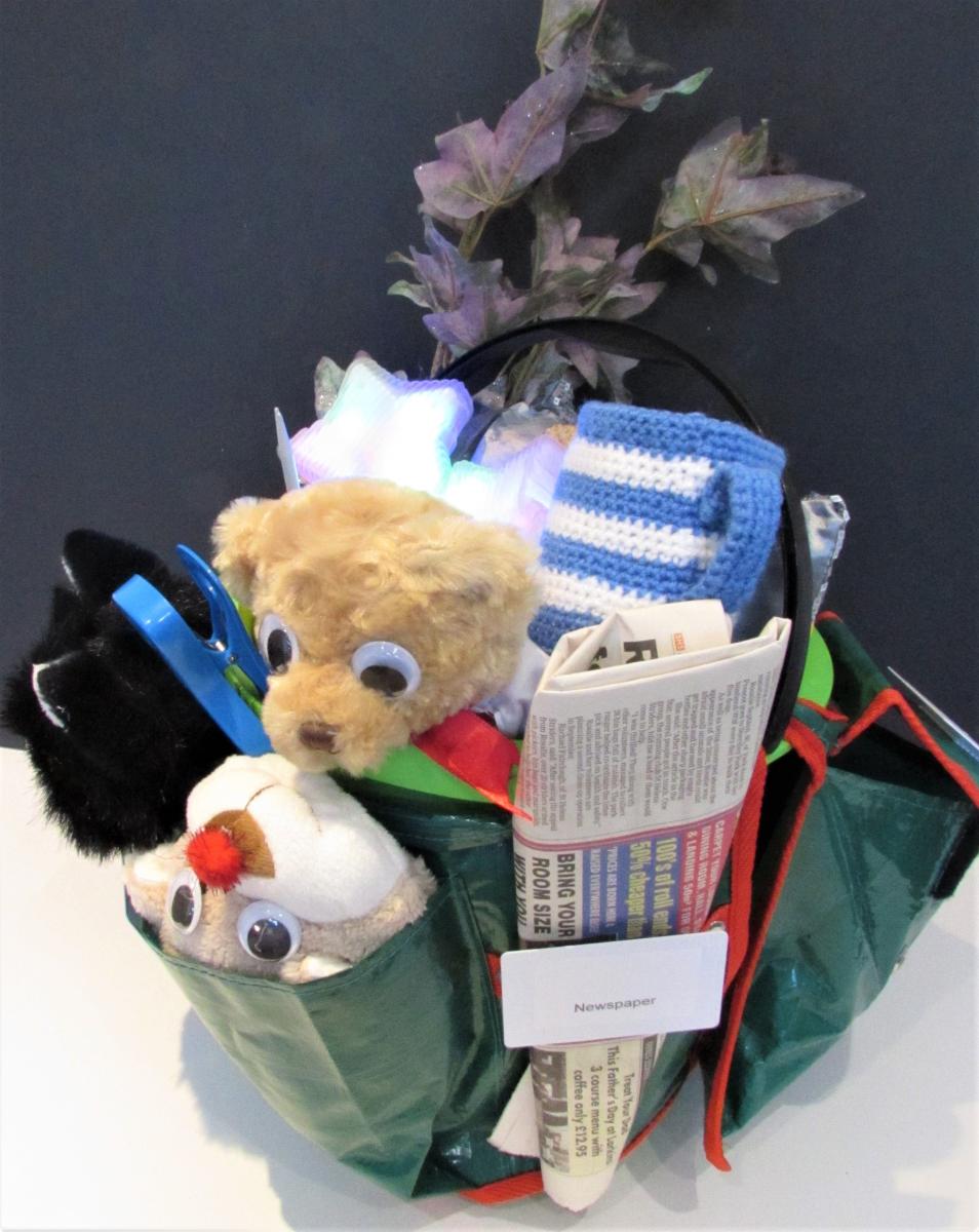 story bucket with stuffed bears, knit mug, newspaper, and other objects